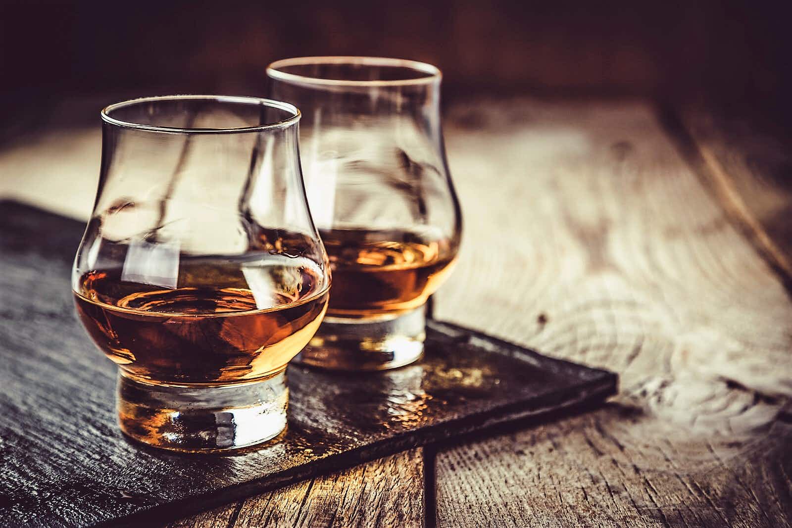 Close up shot of two glasses of whiskey set on a wooden table