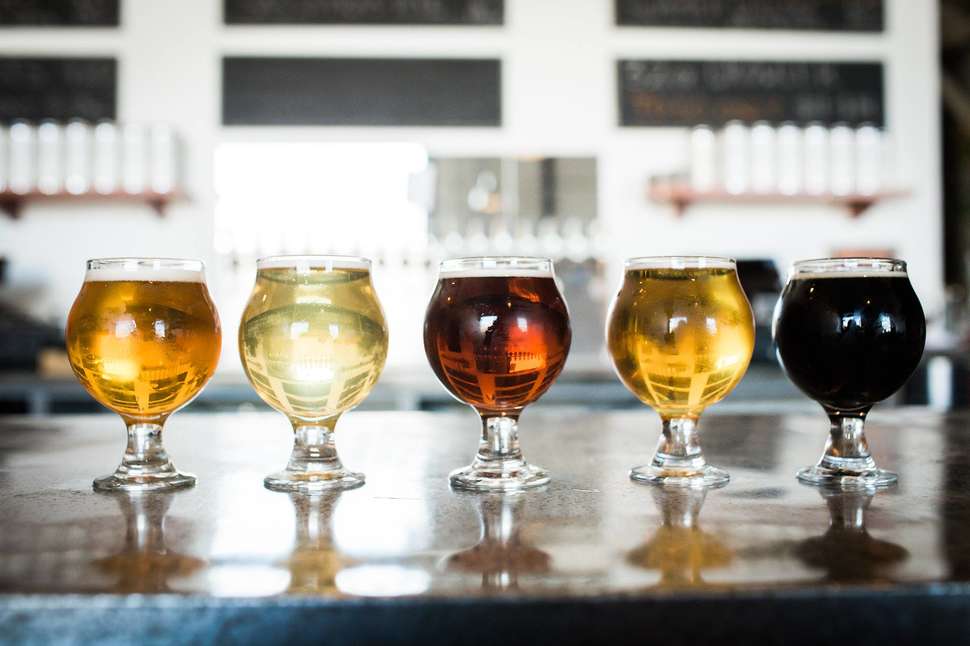 Five different glasses of beer on a bar table inside a microbrewery. San Francisco Food Tours