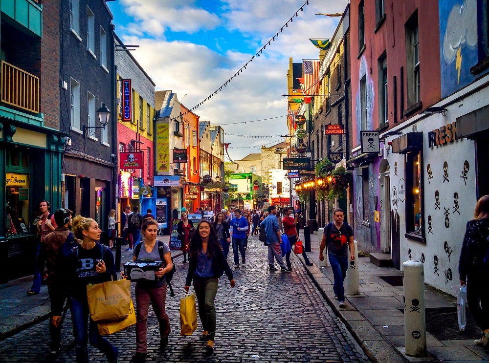Tourists walking along a cobblestone road in a bustling Dublin area