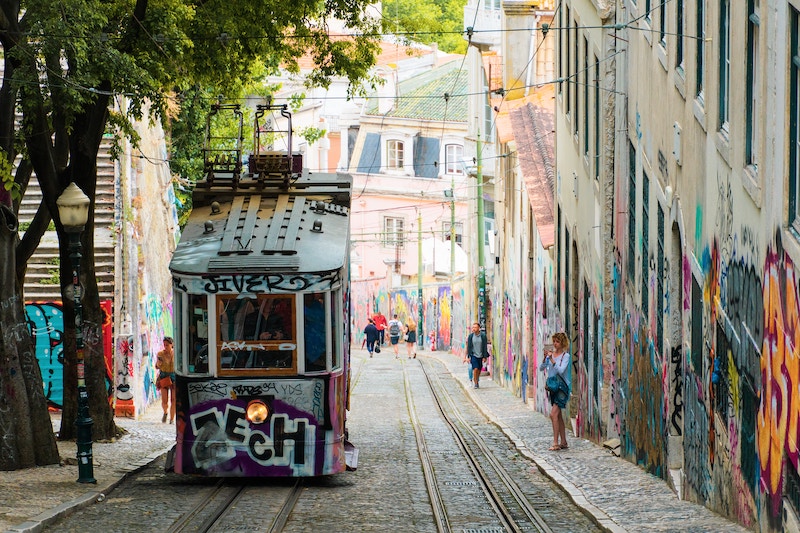 Yellow and white tram climbs steep Lisbon street
