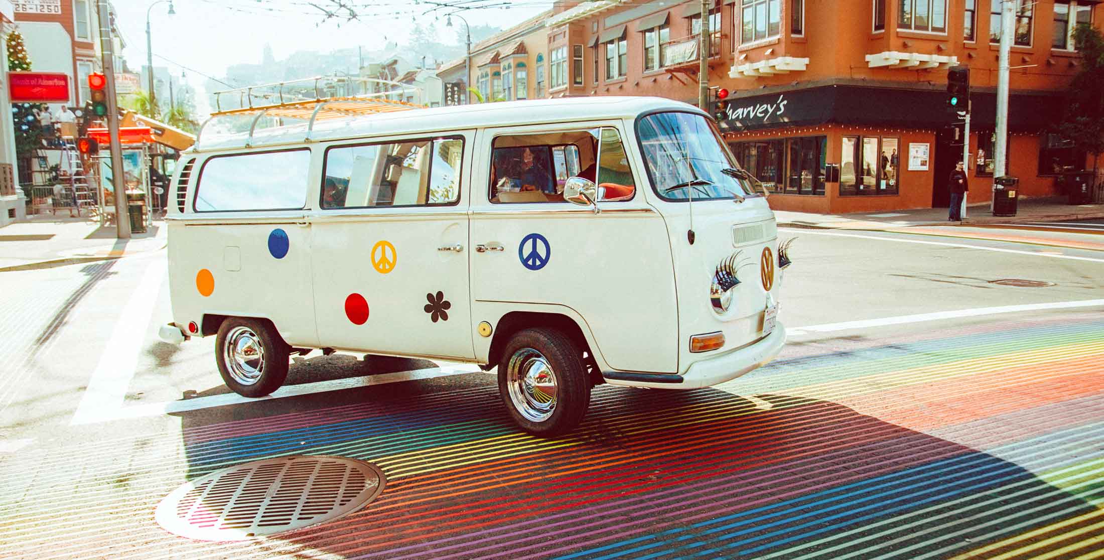 White classic Volkswagen camper bus adorned with hippie decals on a colorful street in San Fransisco 