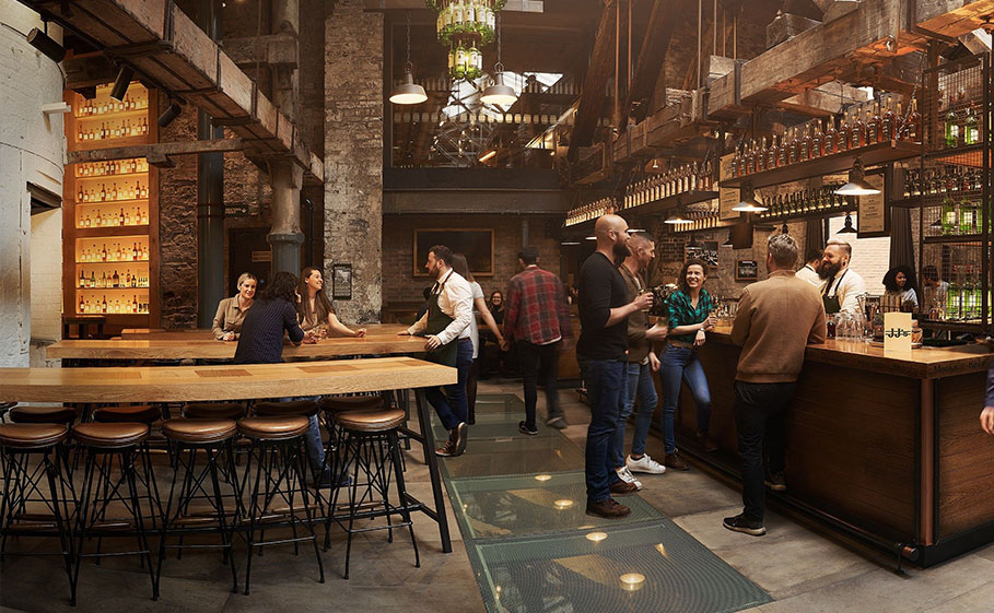 Group of people on a whiskey tour socializing with employees inside an expansive, modern pub.
