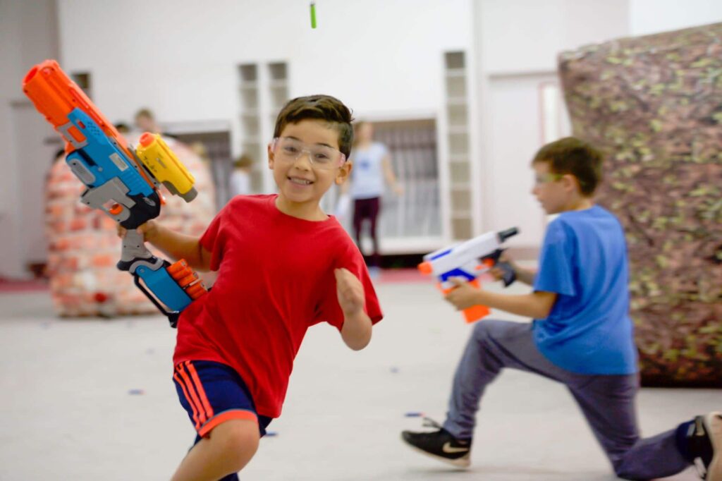 young boy running with toy gun playing NERF hero