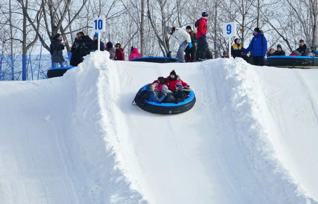 A family sliding down a hill in the snow at La fete des neiges