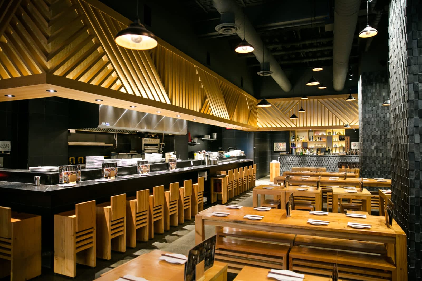Modern Japanese restaurant featuring bar seating and an open kitchen as well as dining tables