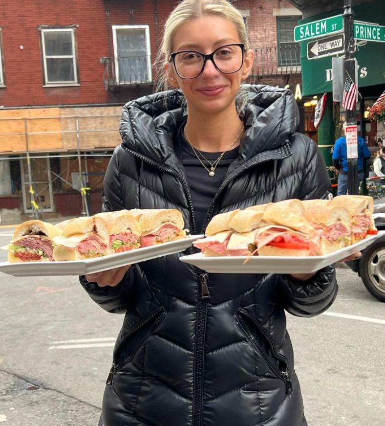 A girl holding two big plates of sandwiches