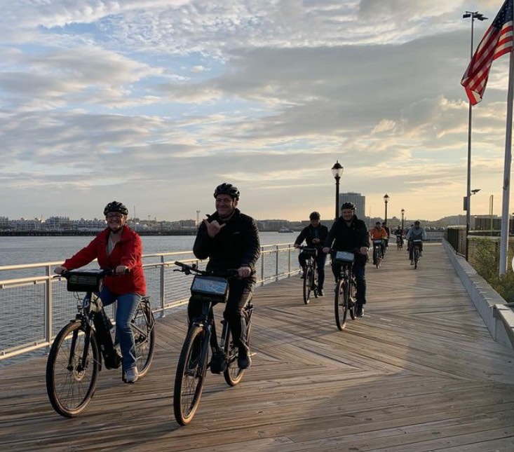 4 people on a bike next to the water